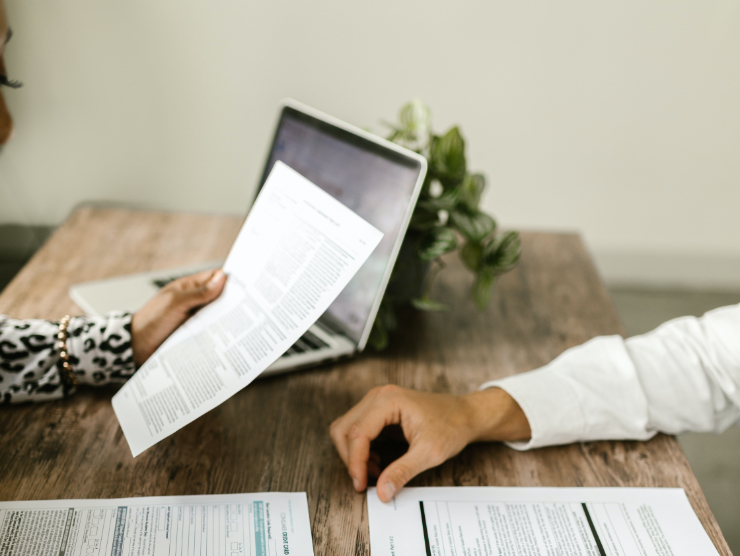 Two people sitting across from one another looking at paperwork, zoomed in on their hands and papers.