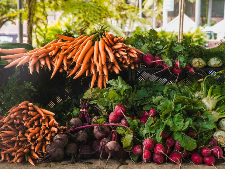 Produce, including bundles of carrots, radishes, and beets, arranged for display.